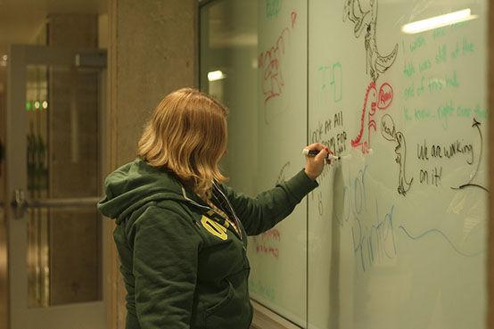 Annie Packman, a senior in the SOJC, tries the new writing walls in Allen Hall.