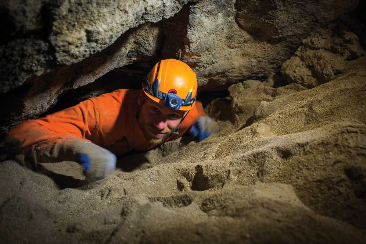 Oregon High Desert Grotto member Jeff Taylor emerges from a tight cave tube at Bear Scat Cave.