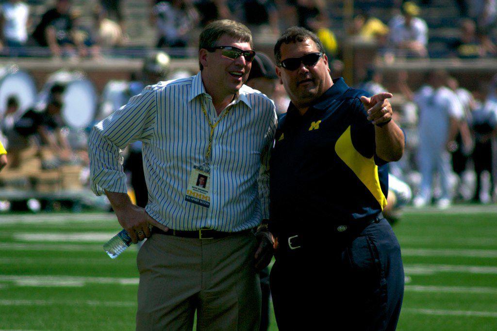 Brady Hoke (right) talking to former Michigan athletic director Dave Brandon. Hoke, who was recently hired as Oregon&#8217;s defensive coordinator, coached Michigan to a 31-20 record in his four-year stint as head coach of the Wolverines (Creative Commons).