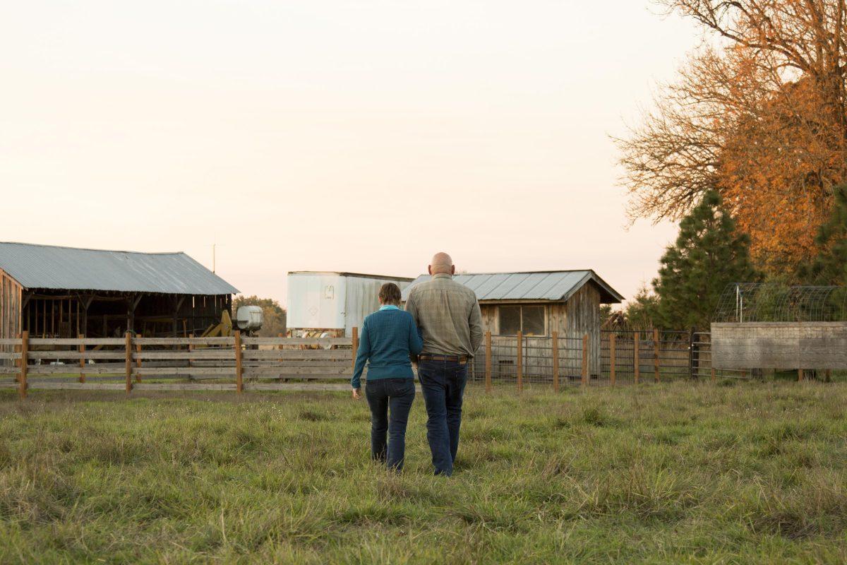 Cherry and Jerry stroll through an area of their property that&#8217;s fenced for their alpaca herd. They keep a barn and a shed for storing tools and materials. The two met at Clackamas Community College in 1972 and have been married for 43 years. Photo By Hetta Hansen