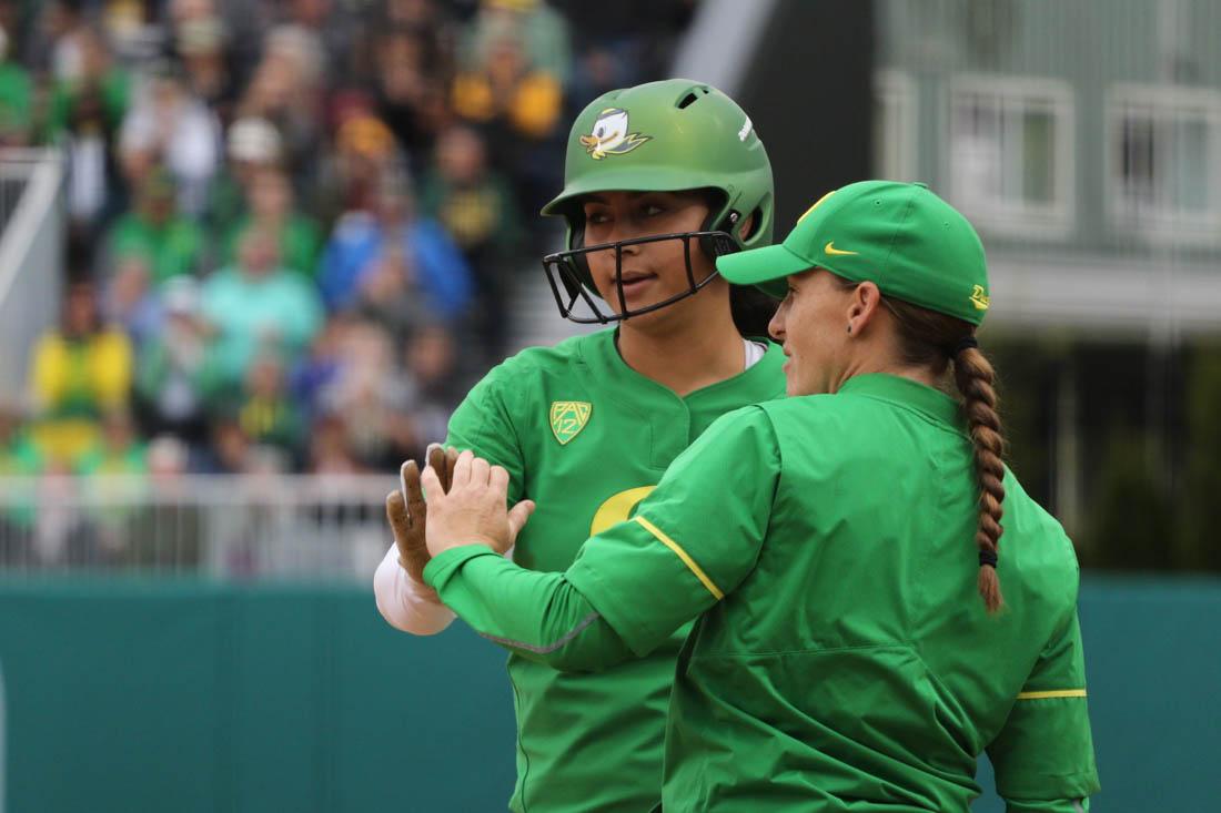 Oregon Ducks Mary Iakopo (17) high fives a coach at first base. The Oregon Ducks play the Utah Swoops at Jane Sanders Stadium in Eugene, Ore. on Sunday May 6, 2018. (Devin Roux/Emerald)