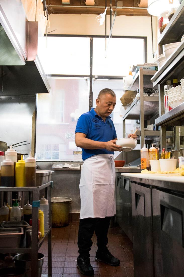 Owner Tiejun Su cooks a meal in the kitchen of Legend of Szechuan. Legend of Szechuan is a modern restaurant located in Eugene, Ore. June 7, 2019. (Madi Mather/Emerald)