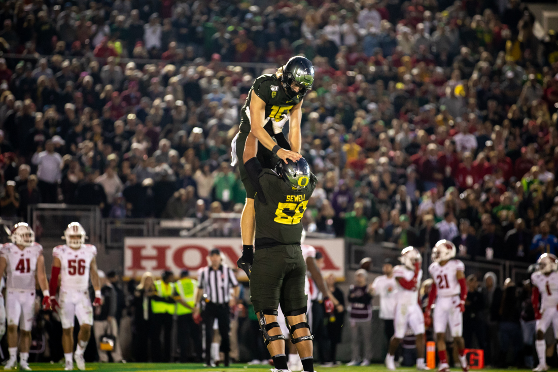 Ducks offensive lineman Penei Sewell (58) picks up quarterback Justin Herbert (10) after his touchdown. Oregon Ducks football takes on Wisconsin for the 106th Rose Bowl Game at Rose Bowl Stadium in Pasadena, Calif. on Jan. 1, 2020. (Maddie Knight/Emerald)