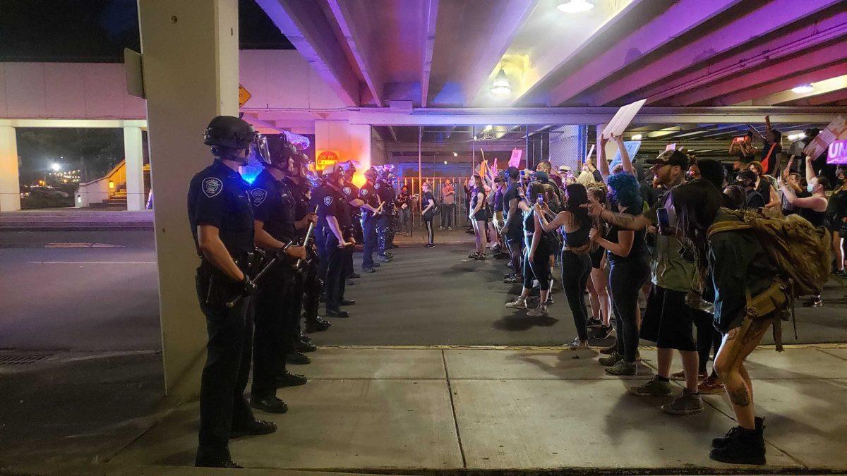 Springfield Police Department officers and Black Unity protesters stand off in a Springfield parking garage. (James Croxton/Daily Emerald)