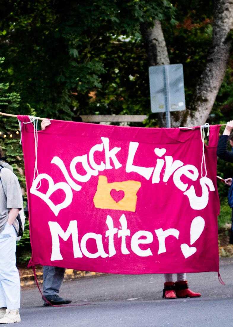 A Black Lives Matter sign is held on the street of the vigil. The Black, Indigenous and People of Color (BIPOC) Project leads a vigil for lives lost to police violence in Eugene, Ore. on June 1, 2020. (Madi Mather/Emerald)