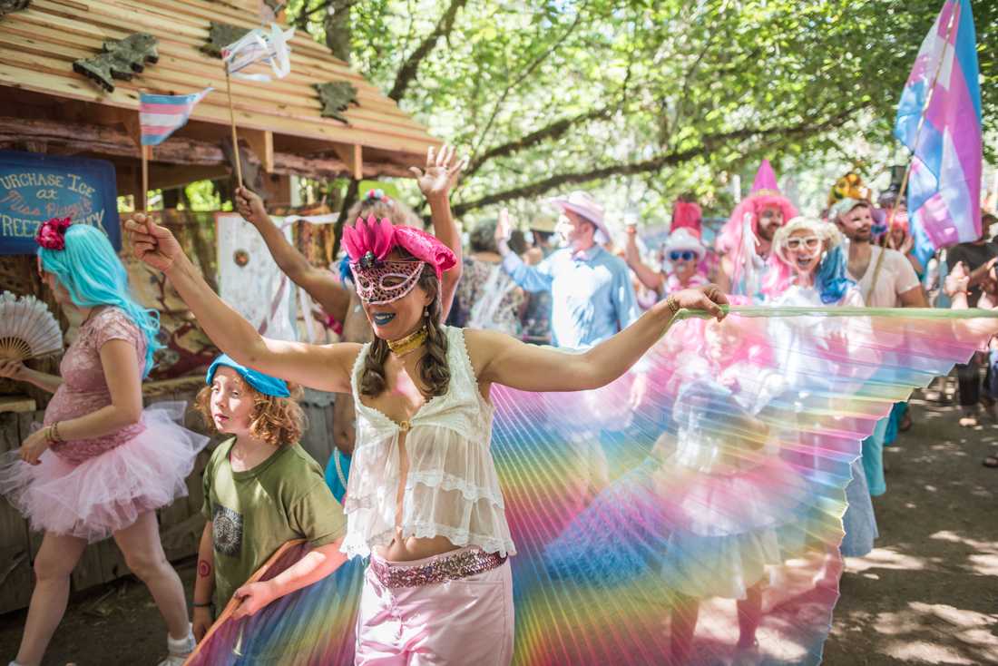 <p>A parade marches down the path waving transgender pride flags to commemorate the 50th anniversary of the Stonewall riots. Oregon Country Fair celebrates 50 years of fun on July 13, 2019 in Veneta, Ore. (Marissa Willke/Emerald)</p>