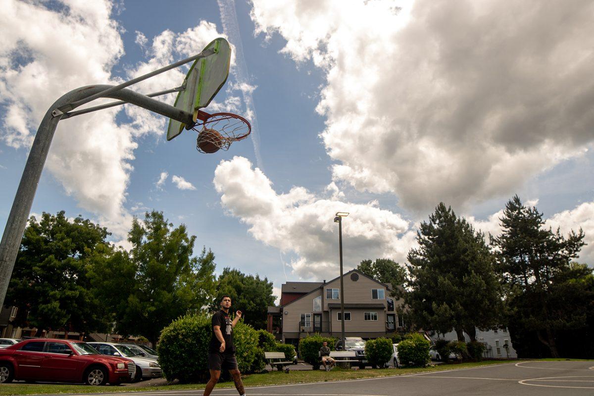 Nathan Reynaga watches a ball go into the net on the basketball courts outside of his apartment. Nathan Reynaga, a masters student at the University of Oregon, has played pick up basketball during the pandemic to stay active and mentally healthy. (Will Geschke/Emerald)