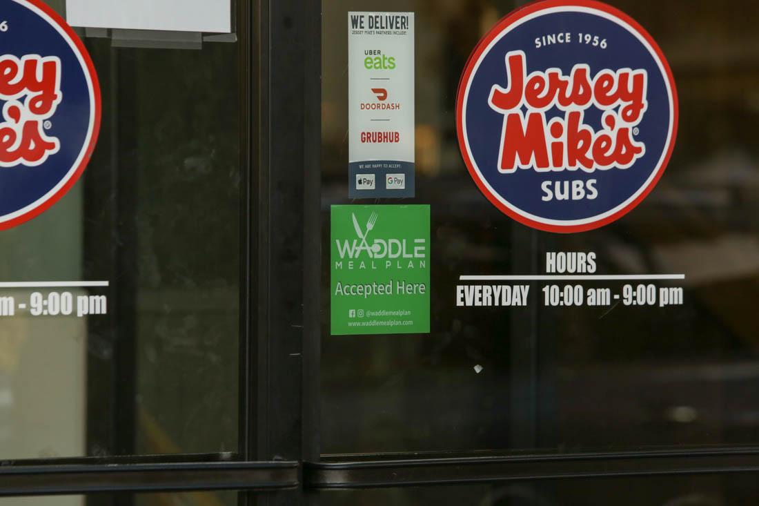 Green signs are displayed on the entrances of where the meal plan is accepted. The Waddle meal plan allows students to explore the restaurants and grocery stores off campus. (Ali Watson/Emerald)