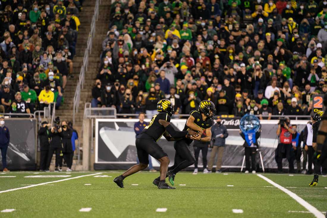 <p>Anthony Brown (13) hands of the ball to Travis Dye (26), for a running play. The Oregon Ducks take on the California Golden Bears at Autzen Stadium in Eugene, Ore., on October 15, 2021. (Serei Hendrie/Emerald)</p>