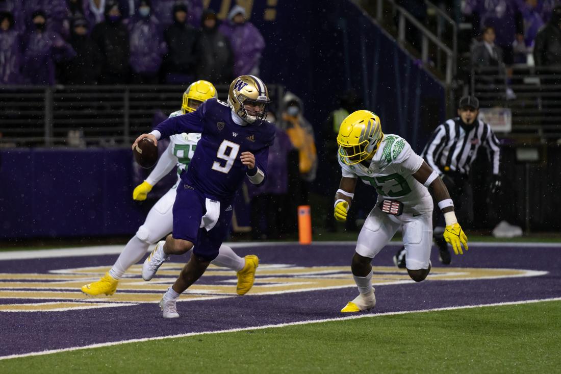 <p>Dylan Morris (9), attemps to outrun an oncoming tackle, and a potential safety, from Jeffrey Bassa (33). The Oregon Ducks take on the Washington Huskies at Husky Stadium in Seattle, Wash., on November 6, 2021. (Serei Hendrie/Emerald)</p>