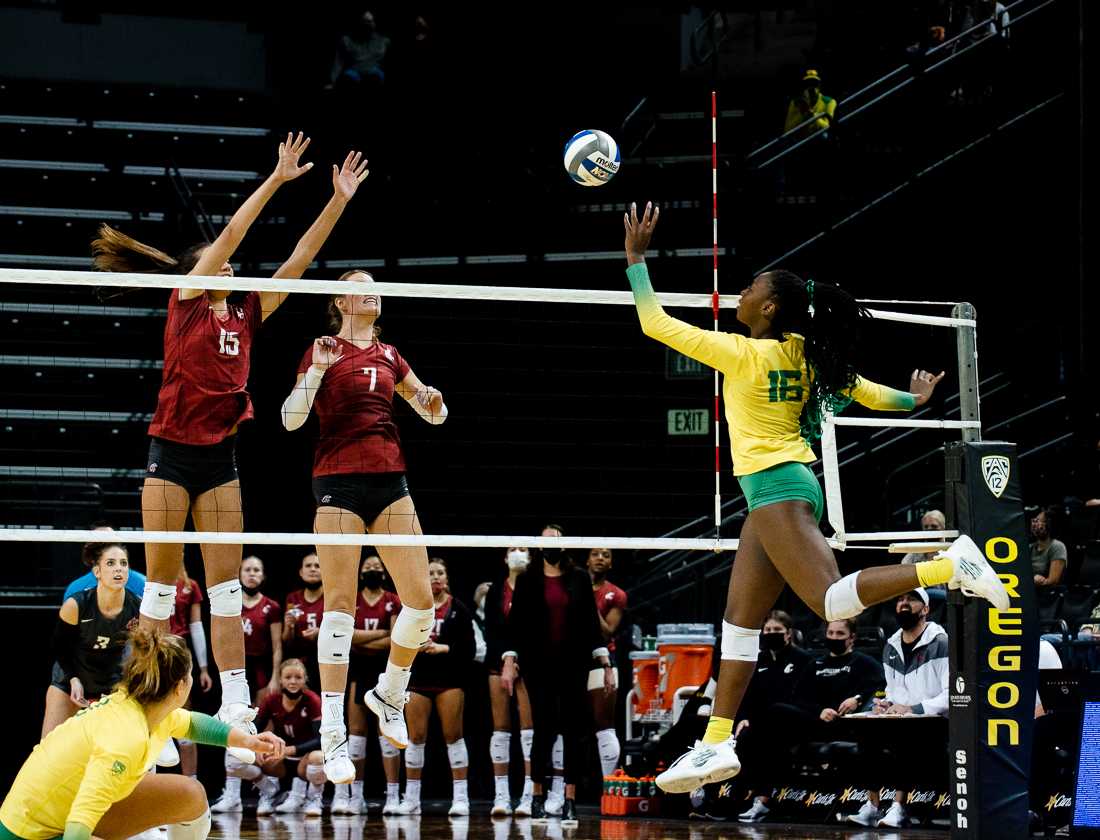 <p>Oregon opposite Gloria Mutiri (16) jumps to spike the ball as her opponents throw their hands up to block. Ducks Women’s Volleyball loses 0-3 to Washington State at Matthew Knight Arena in Eugene, Ore., on October 17th, 2021. (Ian Enger/Emerald)</p>