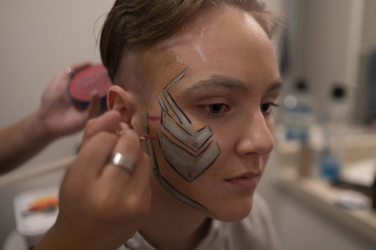 Kira Maddox paints Bleich’s face the afternoon of her performance as a cyborg in “Dragageddon.” Maddox and Bleich have been partners for three years, and Maddox does her best to help prepare for every show.