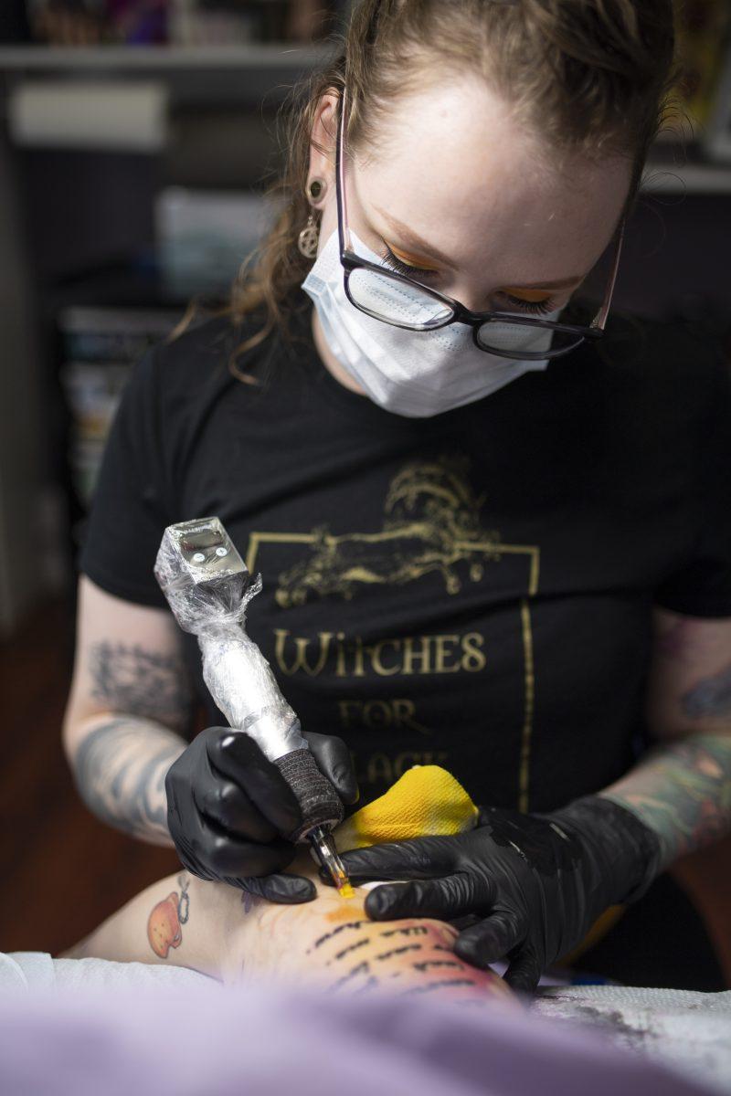 Myth Tattoo co-owner Kinsey Tennison works on a client&#8217;s arm in Eugene, Ore. on January 12, 2022. Myth tattoo offers a welcoming environment to all, a cozy, comfortable environment and skilled artists (Isaac Wasserman/ Emerald)