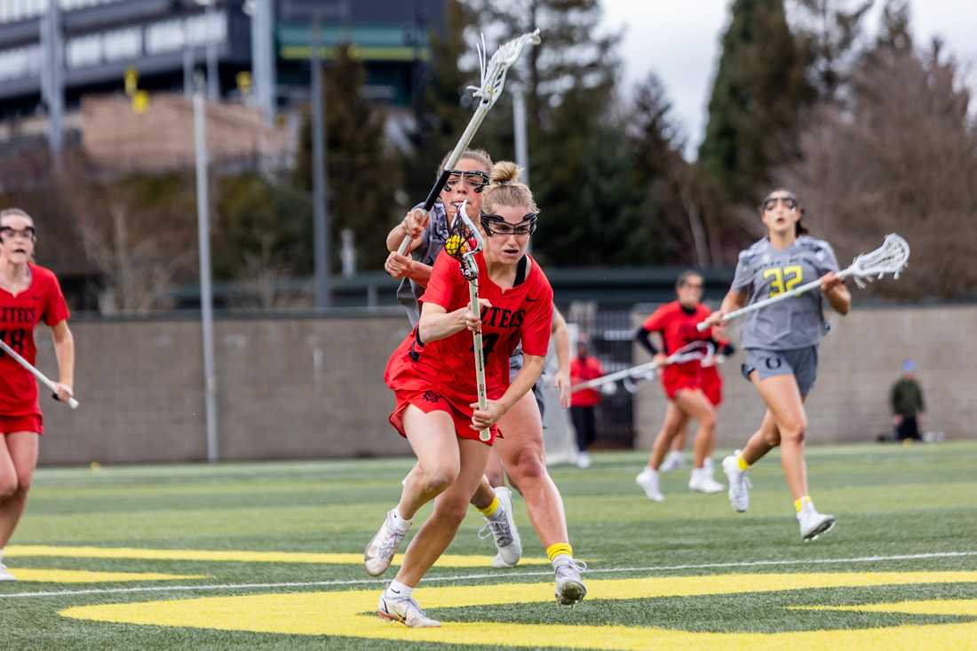 Freshman Gabby Cleveland (06) begins a check on Katelyn Murphy (04). The Oregon Ducks Women&#8217;s Lacrosse team takes on the SDSU Aztecs, on February 27th, 2022. (Molly McPherson/Emerald)