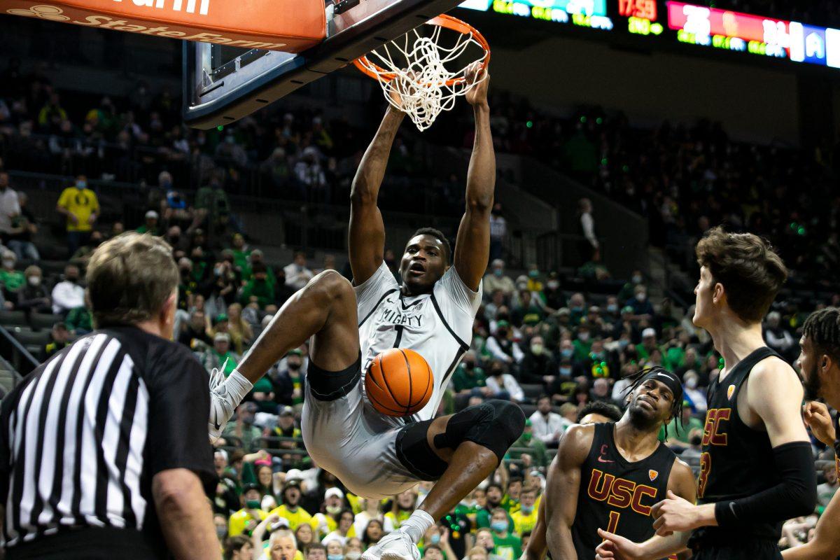 N&#8217;Faly Dante hangs on the rim after a put-back slam. The Oregon Ducks Men&#8217;s Basketball team faces the USC Trojans, on February 26th, 2022, at Matthew Knight Arena. (Liam Sherry/Emerald)