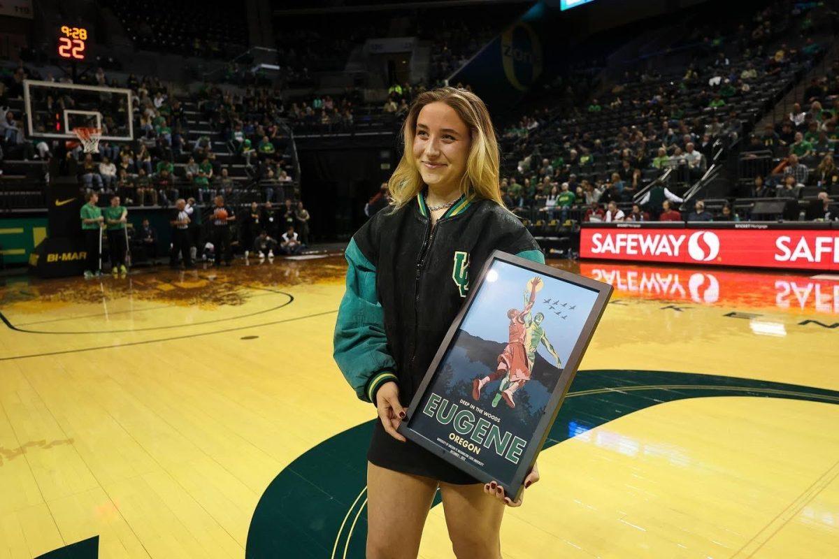 <p>University of Oregon junior Izzy Shilakes poses with the poster she designed for the Oregon men's basketball poster series that is in its inaugural year. (Eric Evans, GoDucks) </p>