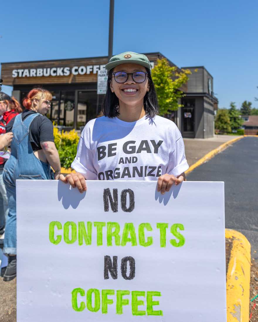 Nick Vuong stands with a sign that reads &#8220;no contracts no coffee.&#8221; Starbucks employees stand in protest against homophobia and union busting within Starbucks&#8217; leadership outside the Villard and Franklin Starbucks store. (Molly McPherson/Emerald)