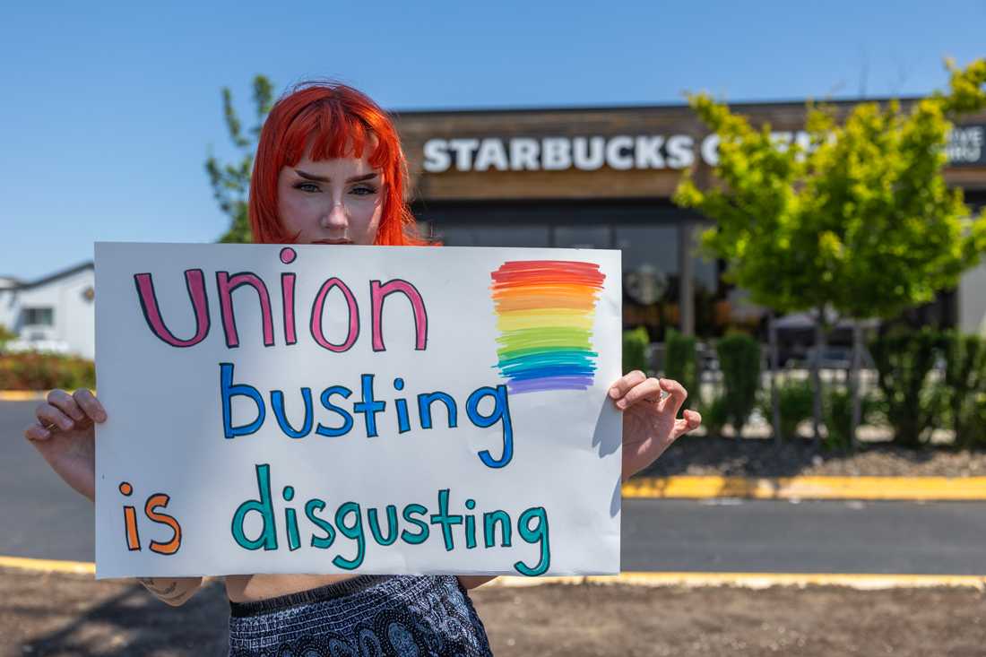 A protester stands with a sign that reads &#8220;union busting is disgusting.&#8221; Starbucks employees stand in protest against homophobia and union busting within Starbucks&#8217; leadership outside the Villard and Franklin Starbucks store. (Molly McPherson/Emerald)