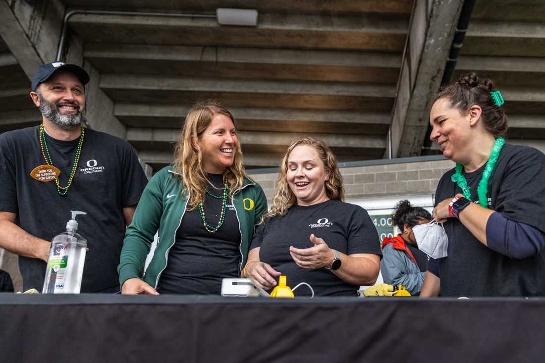 <p>Concession volunteers smile and laugh after they worked together to figure out how to apply a discount to an order. Hundreds of workers flock to and around Autzen Stadium on gamedays, their work is often overlooked by the thousands of fans who attend the game. (Molly McPherson/Emerald)</p>