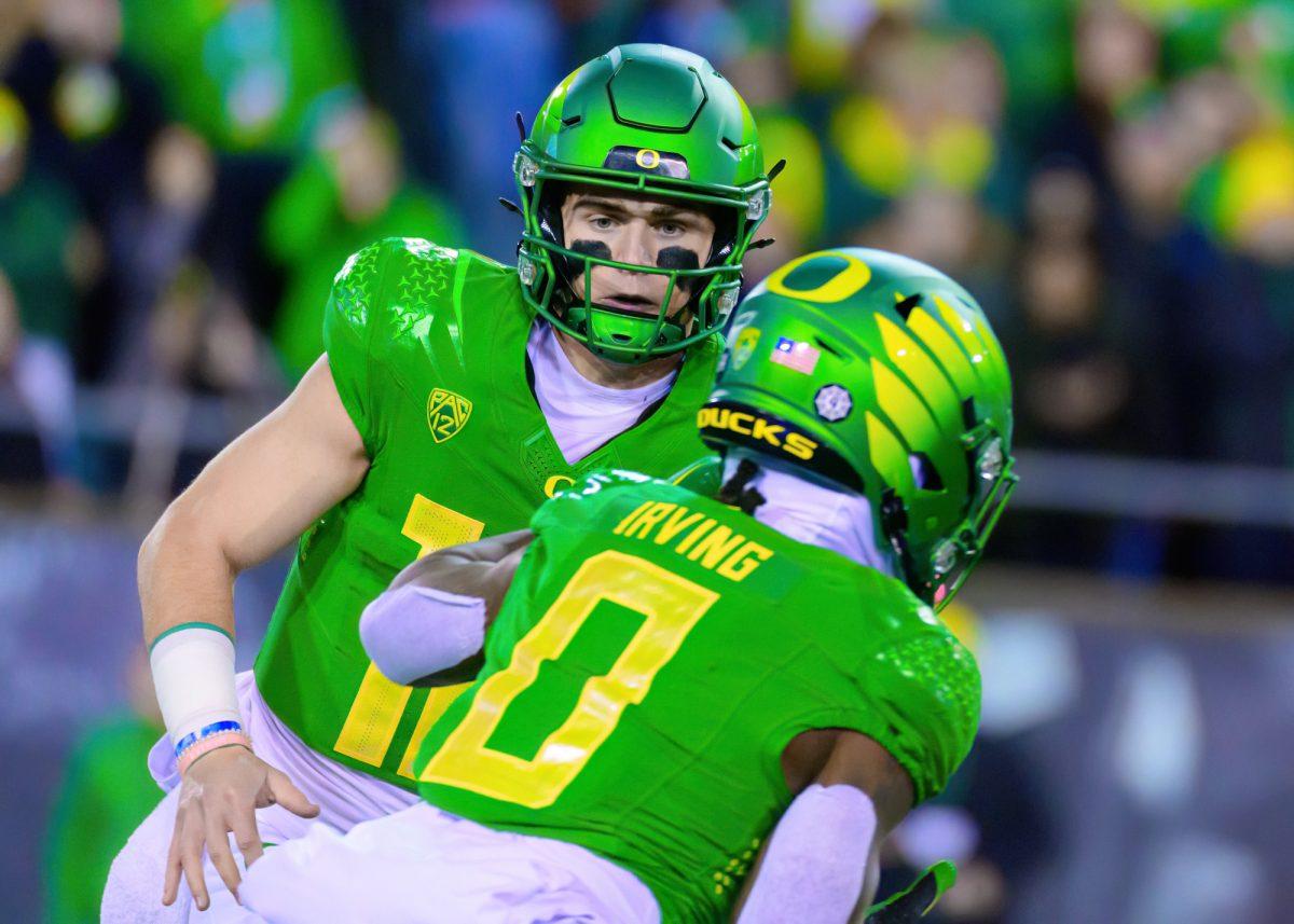 Oregon QB Bo Nix (10) hands off the ball to RB Bucky Irving (0) for a first down. The University of Oregon Ducks Football team defeated Oregon State University 31-7 in a home match at Autzen Stadium in Eugene, Ore., on Nov. 24, 2023. (Eric Becker/Emerald)