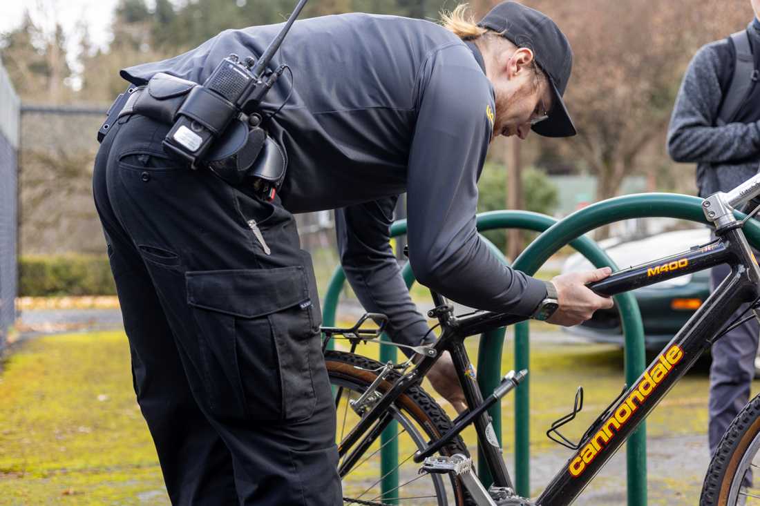 Community Service Officer Bo Morris demonstrates how to properly lock up a bike on a standard rack. Active bike theft continues to increase on the University of Oregon campus in Eugene, Ore. (Kemper Flood/ Emerald)