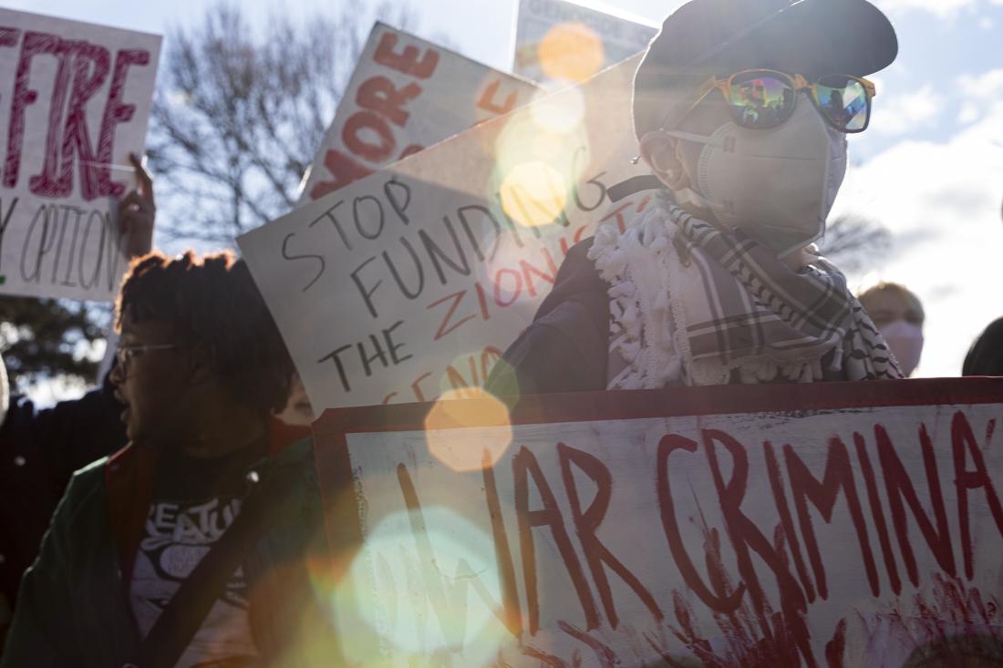 Protesters march carrying signs supporting a "boycott, divest, sanction" movement, among other anti-war sentiments. Students and community members gathered and marched in support of a ceasefire to the Israel-Hamas war on Feb. 10, 2024. (Alex Hernandez/Emerald)