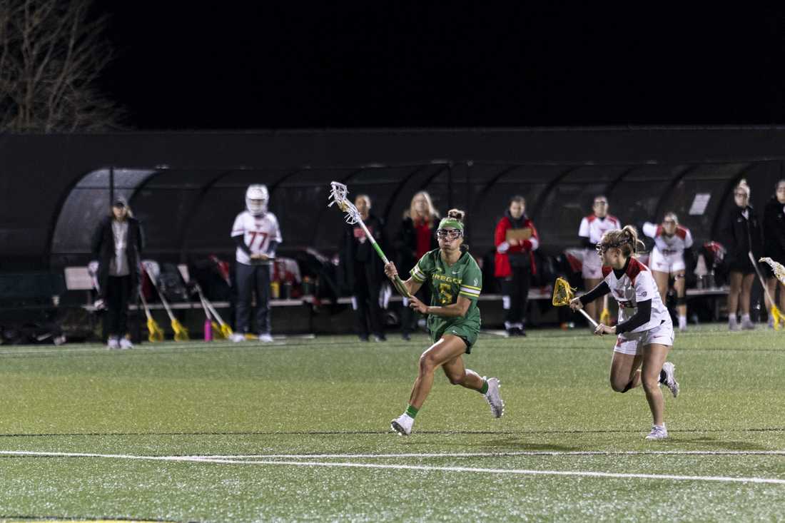 Oregon attacker Morgan McCarthy (5) carries the ball down the field while Youngstown State midfield Grace Run (23) defends. The Oregon Women's Lacrosse team won their match 19-8 against Youngstown State University at Pape Field on Feb. 9, 2024. (Alex Hernandez/Emerald)