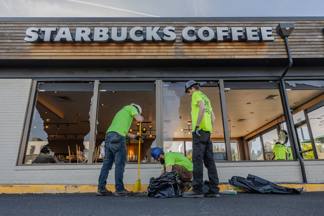 Workers chat while they sweep broken glass off the pavement outside the store. Early morning Wednesday May 15, 2023 the Starbucks on Franklin Boulevard had its windows smashed and vandalized. (Molly McPherson/Emerald)