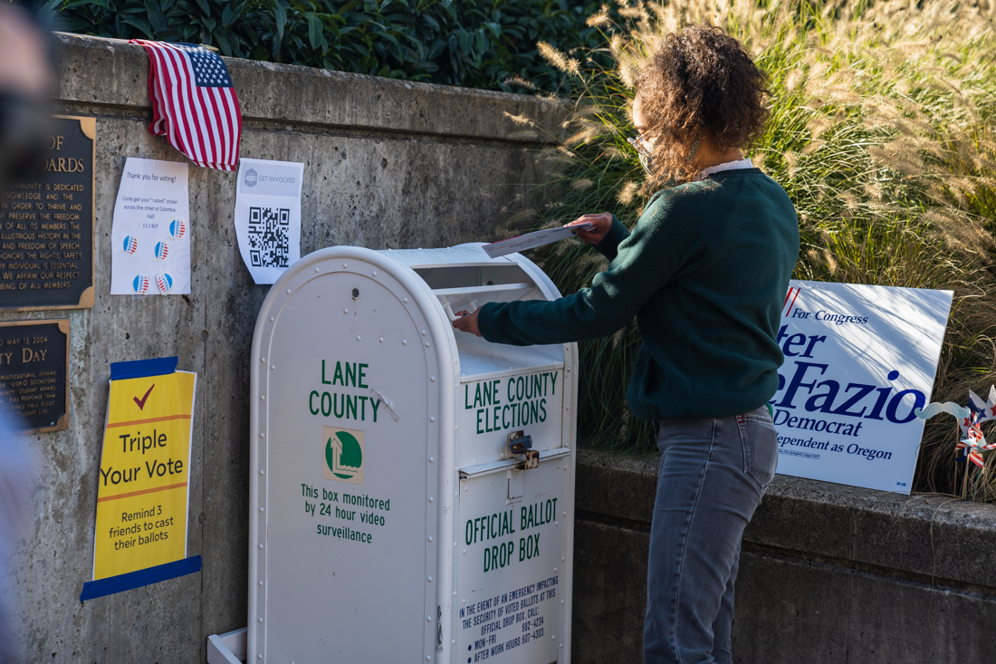 A student drops of their ballot as a demonstration of the importance of casting a vote safely. University of Oregon College Democrats host a socially distanced voting rally at the Erb Memorial Union Amphitheater in Eugene, Ore. on Nov. 2, 2020. (DL Young/ Emerald)