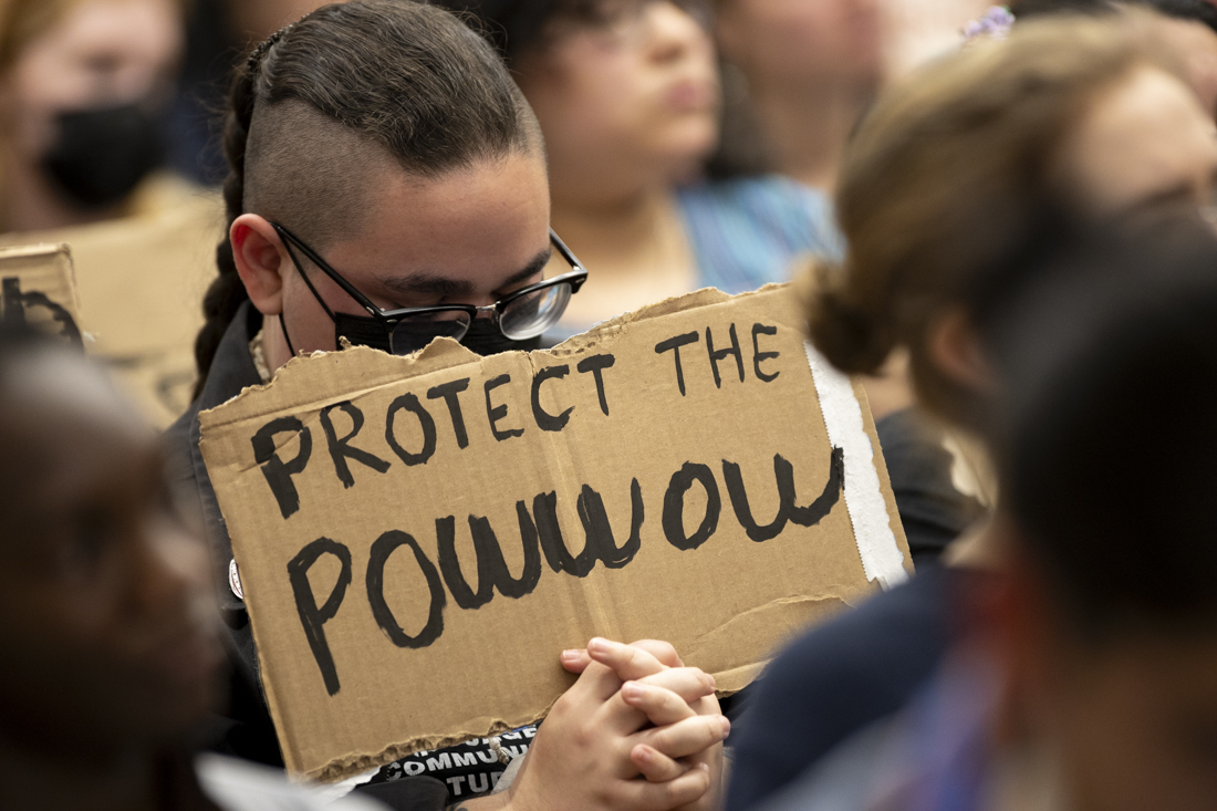 An attendee of the sit-in holds a sign in support of the powwow at the ASUO senate meeting on March 13, 2024. Over 150 students and community members protested the decision made by the ASUO to schedule the spring concert on the same weekend as the 56th Annual Mother's Day Powwow, a community and cultural event planned by the Native American Student Union. (Alex Hernandez/Emerald)