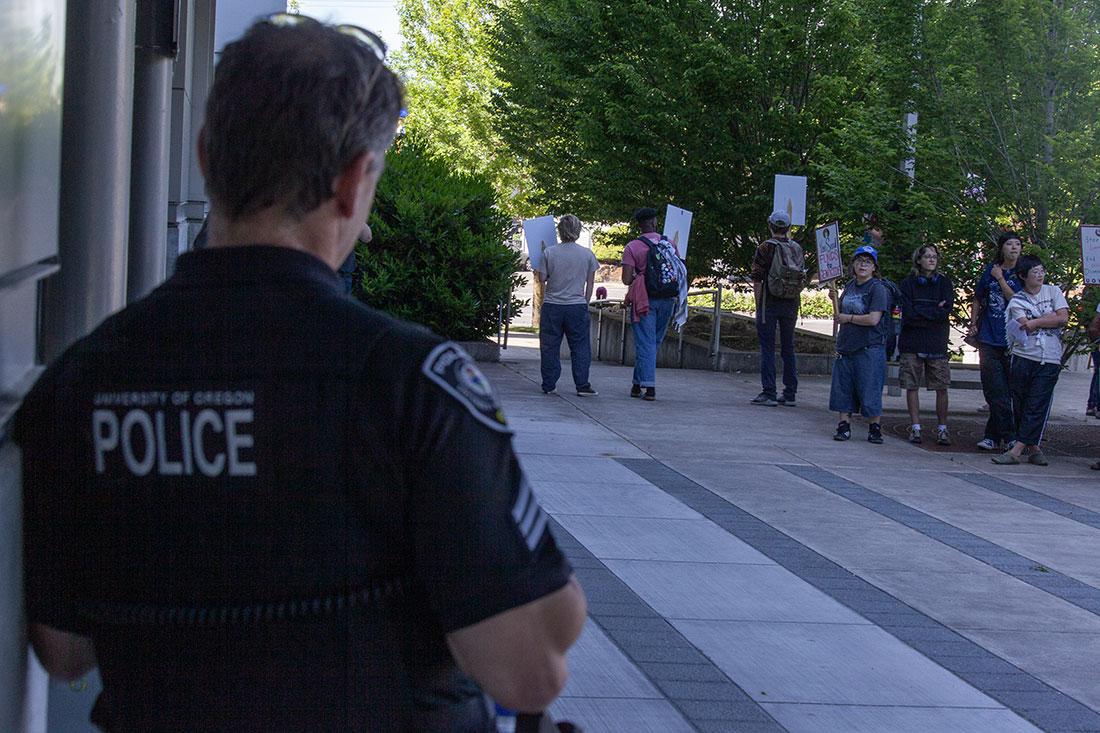 A University of Oregon Police officer watches the gathered crowd of protestors outside of Matthew Knight Arena. Thursday, President of the University of Oregon, Karl Scholtz, attended his investiture at the Matthew Knight Arena, celebrating his formal installment as president of the university. Pro-Palestine protestors interrupted the ceremony as Scholtz accepted the Centennial Medallion with a deluge of chants. After a brief confrontation, protestors moved outside to a separate entrance where they continued their protest. (Miles Cull/Emerald)