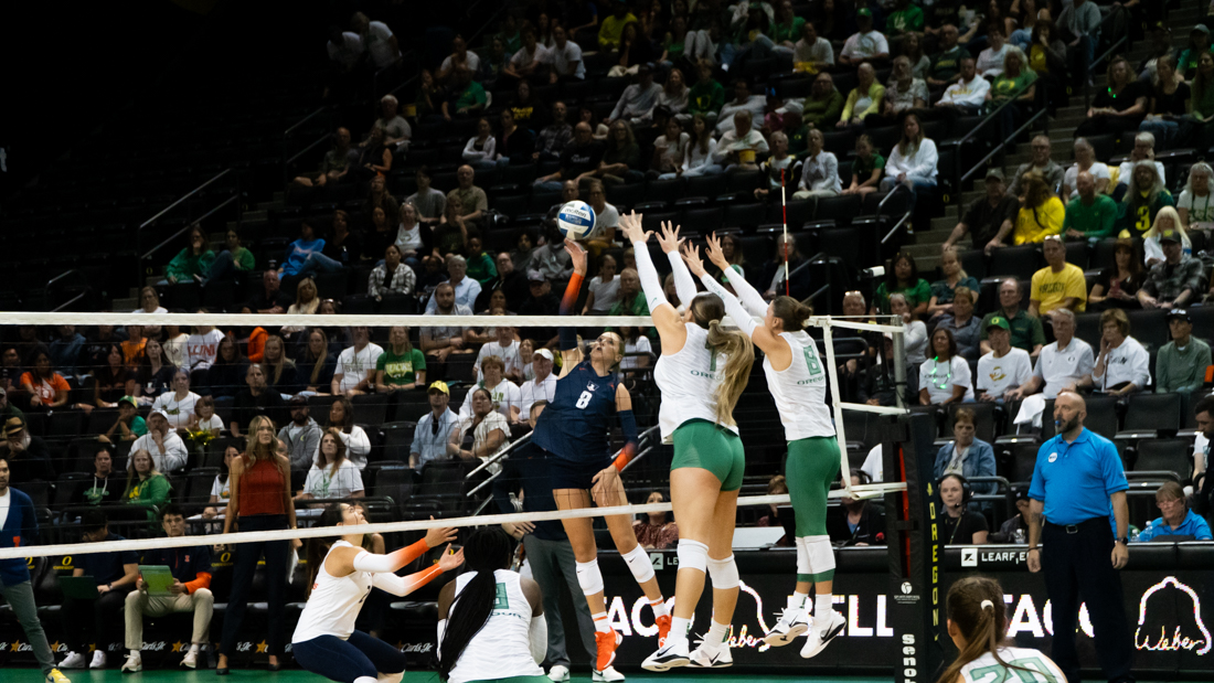 Two Oregon volleyball players blocked a fast spike from an Illinois player, defending their side of the court. (Saj Sundaram/Emerald)