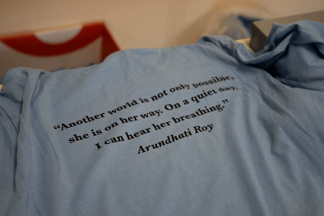 A T-shirt displays a quote by Arundhati Roy: "Another world is not only possible, she is on her way. On a quiet day, I can hear her breathing." Desi Fest, at Lane Community College, celebrated South Asian culture with performances, food, and activities on Oct. 5, 2024. (Mason Cruz/Emerald)