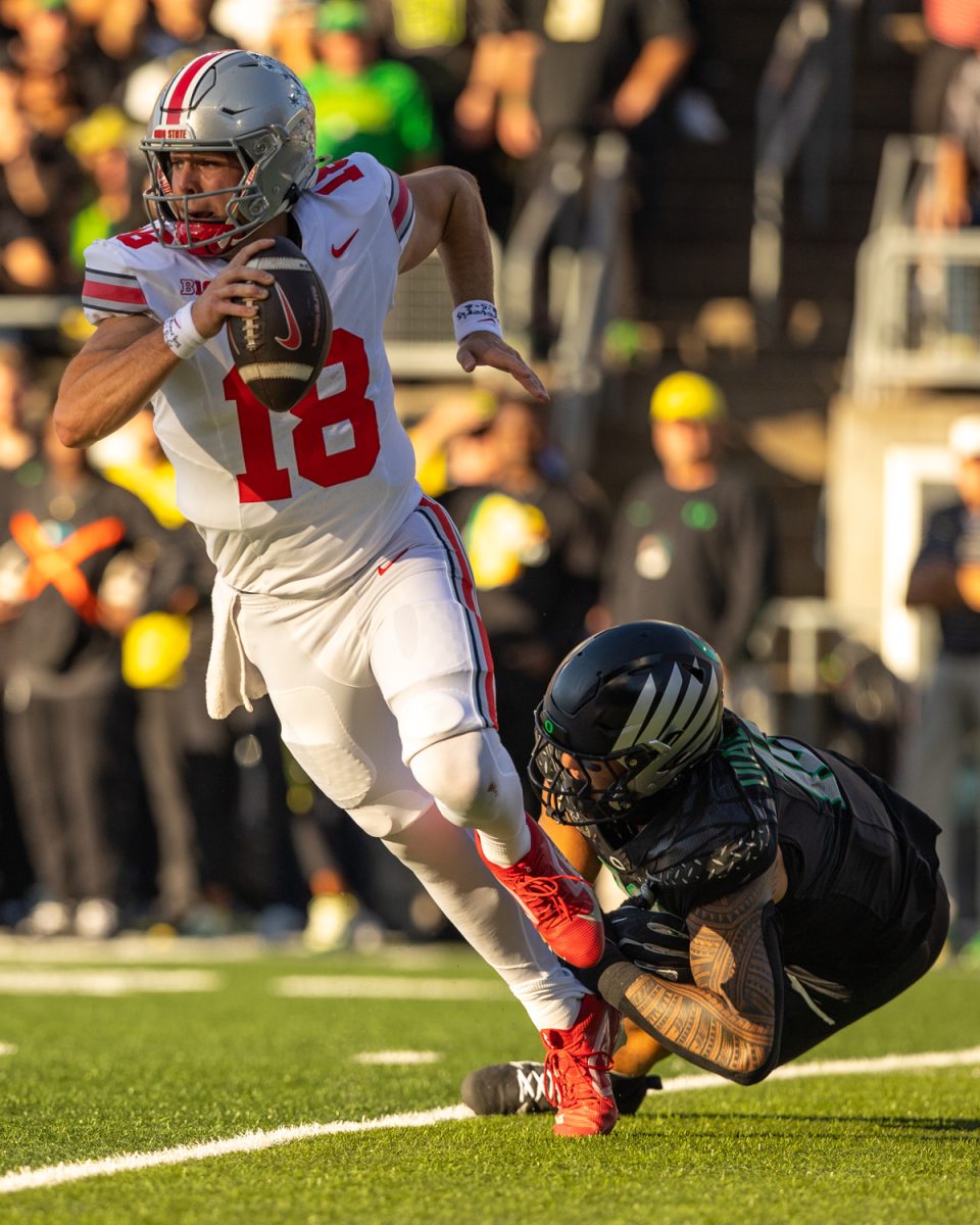 Ohio State quaterback Will Howard (18) tries to get out of a tackle by Duck Matayo Uiagalelei (10). The number 3 ranked Oregon Ducks football team takes on the number 2 ranked Ohio State University Buckeyes on Oct. 12, 2024, at Autzen Stadium in Eugene, Ore. (Molly McPherson/Emerald)