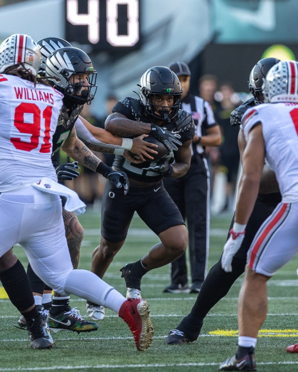 Jordan James (20) takes a handoff from Dillon Gabriel (8). The number 3 ranked Oregon Ducks football team takes on the number 2 ranked Ohio State University Buckeyes on Oct. 12, 2024, at Autzen Stadium in Eugene, Ore. (Molly McPherson/Emerald)