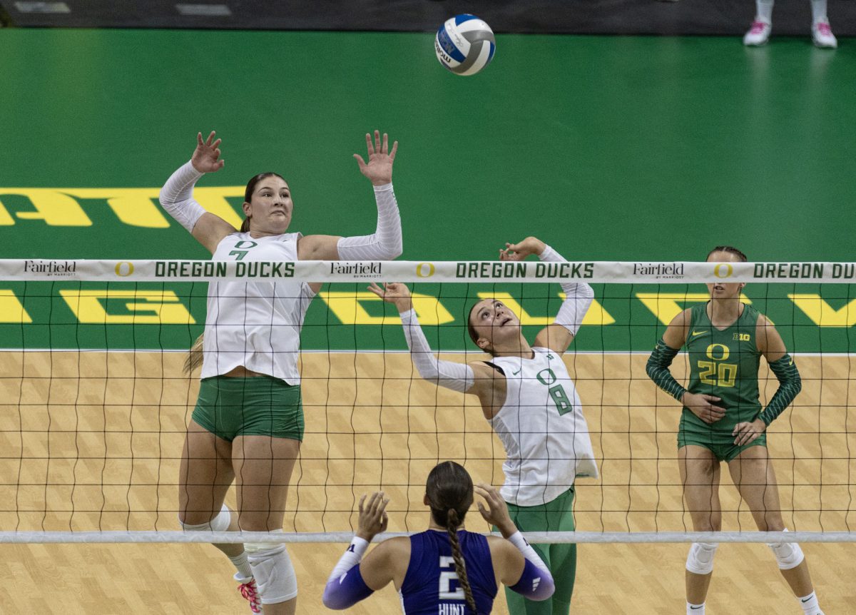 Oregon middle blocker Colby Neal (7) and setter Cristin Cline (8) meet in the air to threaten a spike. The University of Oregon Ducks fought tooth and nail for a 3-2 win over the University of Washington Huskies Sunday. Now 13-2 in the season, the Ducks next play the University of Wisconsin Badgers Oct. 18. (Miles Cull/Emerald)