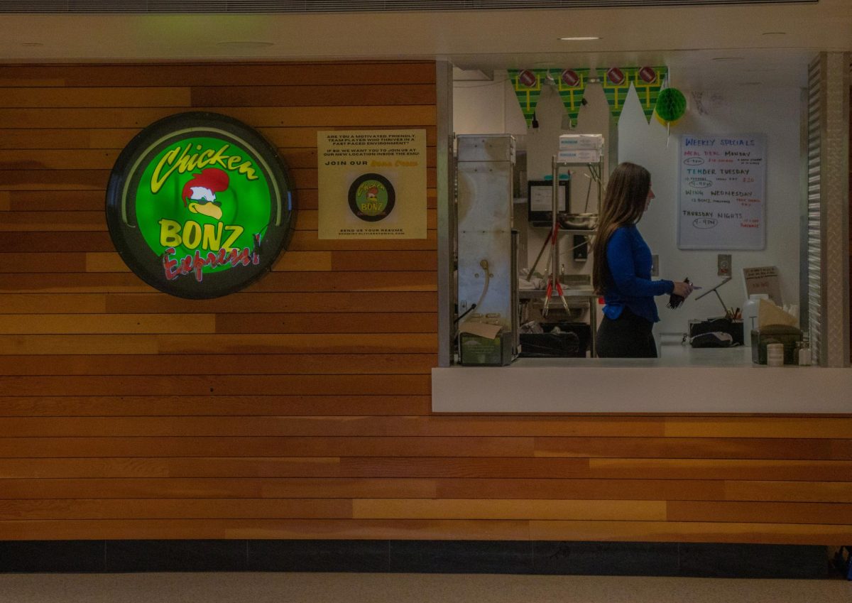 An employee of Chicken Bonz works at the front register in the Erb Memorial Union at the University of Oregon. (Alyssa Garcia/Emerald) 