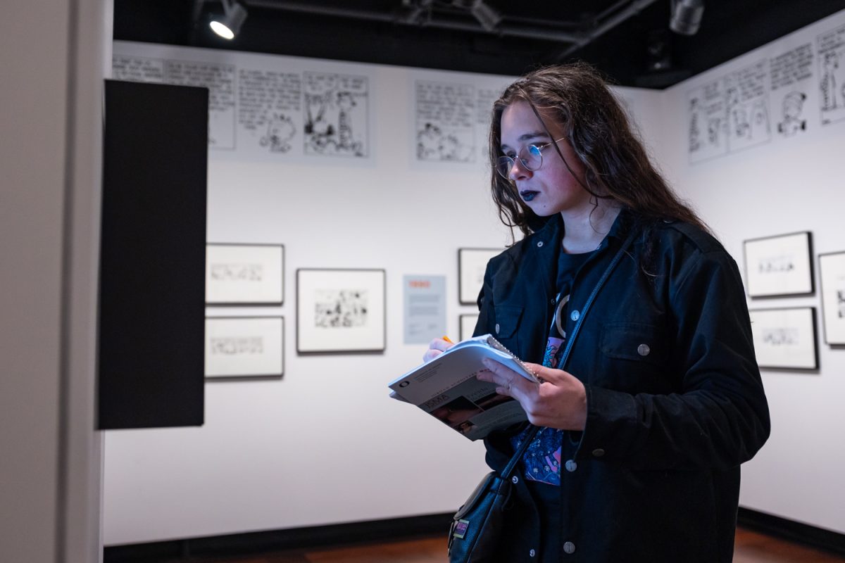 Jesse, an Art History student, sketches while looking at the digital display up in the exhibition. Curated by Kate Kelp-Stebbins, Associate Professor of English in Comics and Cartoon Studies, the “It's (Still) A Magical World, Hobbes, Ol' Buddy” exhibit is on display at the Jordan Schnitzer Museum of Art until Jordan Schnitzer Museum of Art. (Molly McPherson/Emerald)