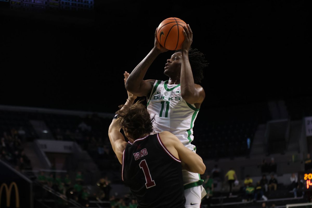 Oregon forward Mookie Cook (11) leaps over Troy forward Thomas Dowd (1). The University of Oregon Ducks defeated the Troy University Trojans 82-61 on Sunday, November 17. Now 4-0 in the season, the Ducks will play the Oregon State Beavers on November 21. (Miles Cull/Emerald)