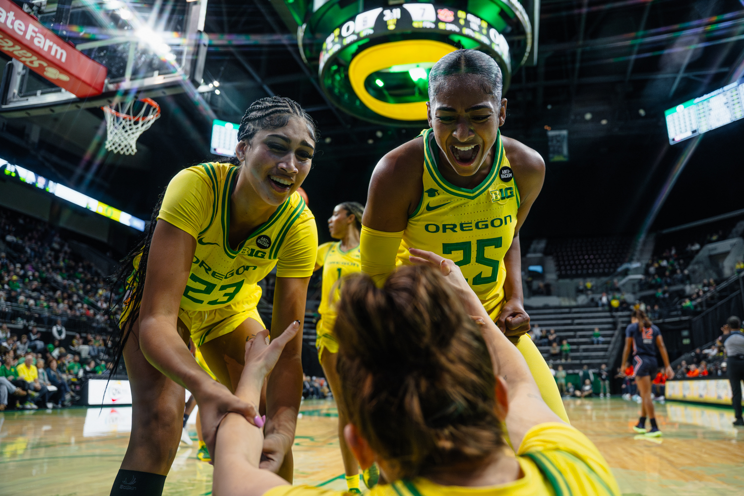 Sarah Rambus (23) and Deja Kelly (25) celebrate while helping up teammate Elisa Mevius (8). The Oregon Ducks women's basketball team takes on the Auburn Tigers on Nov. 20, 2024, at Matthew Knight Arena in Eugene, Ore. (Jordan Martin/Emerald)