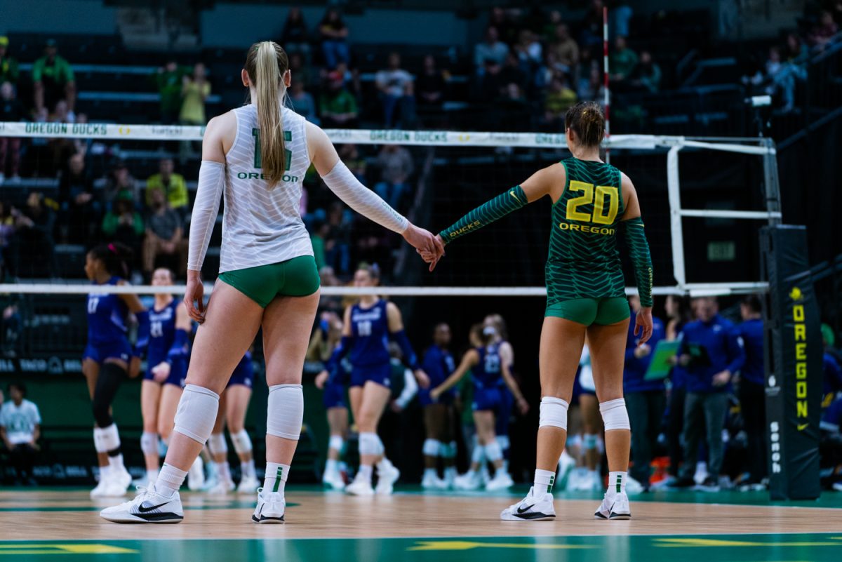 Mackenzie Morris (20) and Mimi Colyer (15) embrace before play. The University of Oregon Ducks Women's Volleyball team defeat the Northwestern University Wildcats (3-1) in a home match at Matthew Knight Arena in Eugene, Ore., on Nov. 15, 2024. (Rowan Campbell/Emerald).