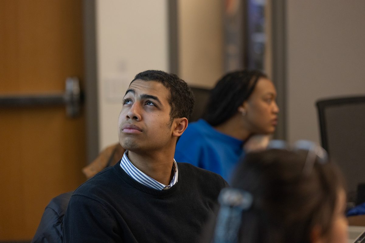 ASUO Speaker of the Legislature, Taliek Lopez-DuBoff, peering at a presntation from the UO MMA Club. (Miles Cull/Emerald)