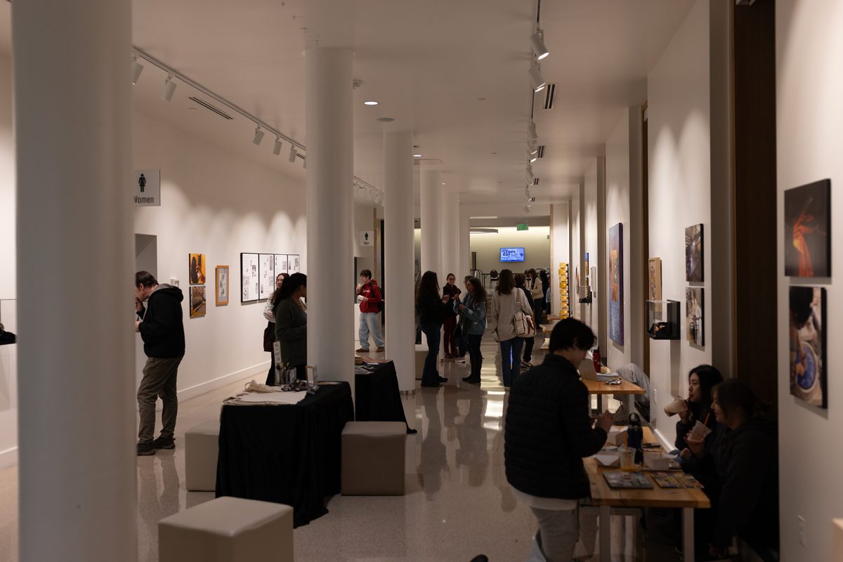 Attendees gather to see the displayed art and enjoy free smoothies and sushi at the Process and Projects Exihibition in the Erb Memorial Union. (Miles Cull/Emerald)