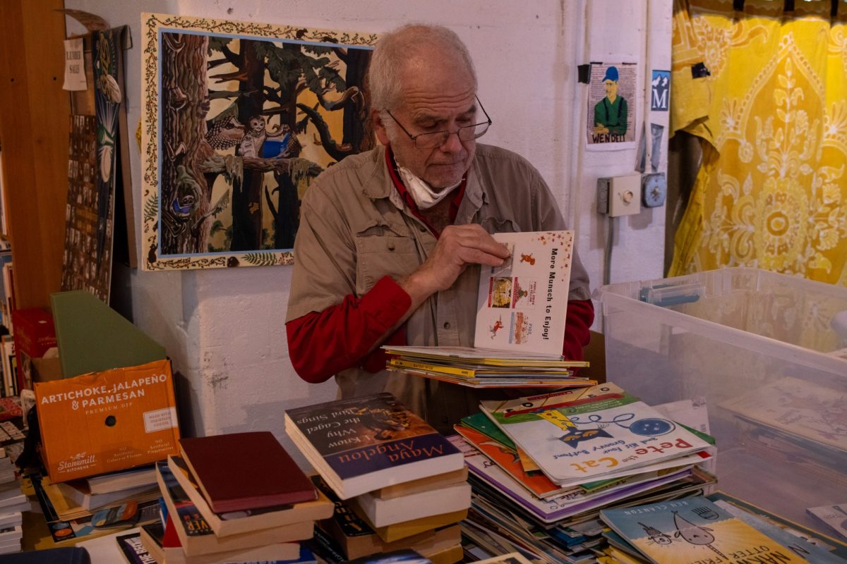 Owner of Tsunami Books, Scott Landfield, sorts a stack of childrens books that the store may buy from a customer. Tsunami Books is an independent bookstore selling a wide selection of used and new titles located in Eugene, Ore. They also sell various artwork made by different artists, and will hold community events, and shows year around.  (Anna Liv Myklebust/Emerald)