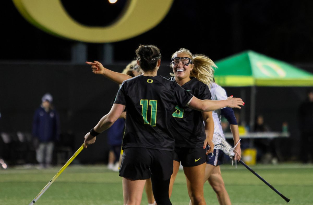 Bri Carrasquillo (11) and Avery Young (15), both attackers for the Ducks lacrosse team, embrace after a second half goal. The Oregon Ducks take on the Butler Bulldogs in their home opener at Pape Field in Eugene, Ore. on Feb. 7, 2025. (Julia Massa/Emerald)