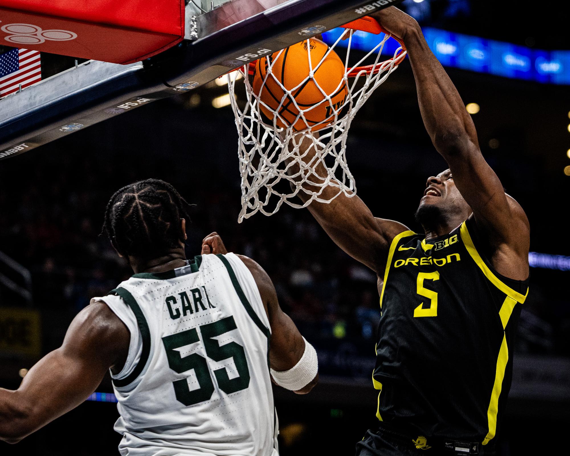 TJ Bamba returns the favor on Carr (55) with a strong dunk of his own to bring some energy back for the Oregon Ducks. The Oregon Ducks take on the Michigan State Spartans in the second round of the Big Ten Tournament at Gainbridge Fieldhouse in Indianapolis, IN, on March 14, 2025. (Jonathan Suni/Emerald)