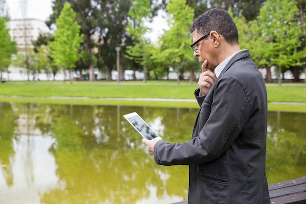 https://img.freepik.com/free-photo/pensive-man-using-tablet-standing-city-park_1262-20294.jpg