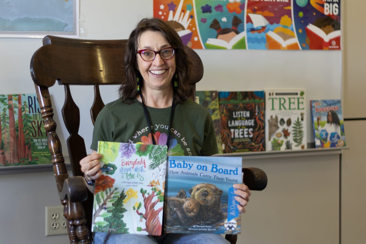 Martha Dyer, the librarian at Cesar E. Chavez Elementary school in Eugene, Ore., poses for a portrait with books about otters and trees. She read the book about otters to her group of kindergarteners on April 17, 2025. (Julia Massa/Emerald)
