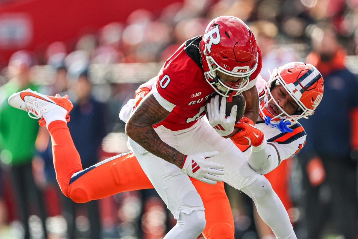 Nov 23, 2024; Piscataway, New Jersey, USA; Rutgers Scarlet Knights wide receiver Dymere Miller (0) is tackled by Illinois Fighting Illini defensive back Xavier Scott (14) during the first half at SHI Stadium. Mandatory Credit: Vincent Carchietta-Imagn Images