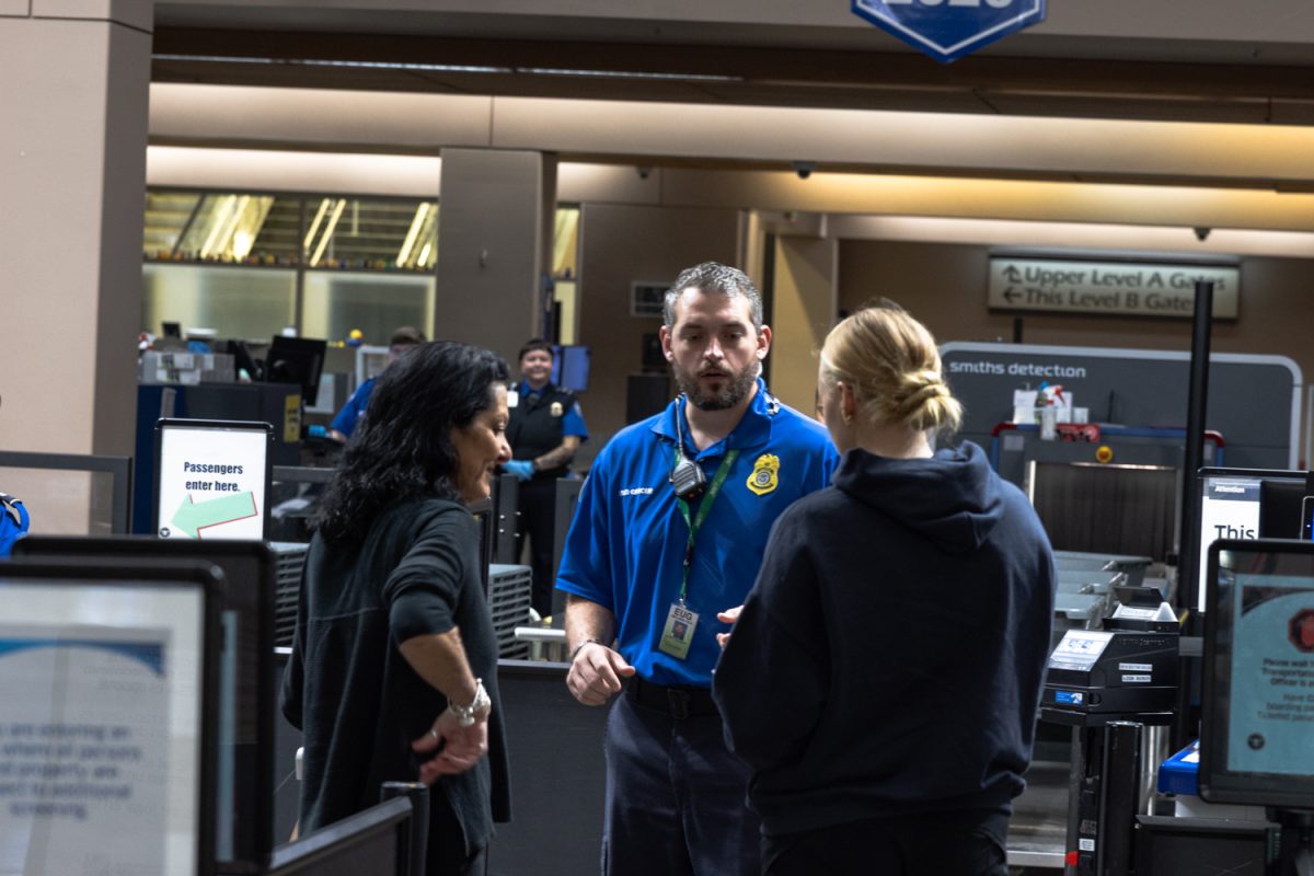 TSA agent works with a college student and woman to resolve confusion. Travelers pass through security at the Eugene airport on Sunday, Oct. 19, 2025, in Eugene, Ore. (Owen Burriss/Emerald)